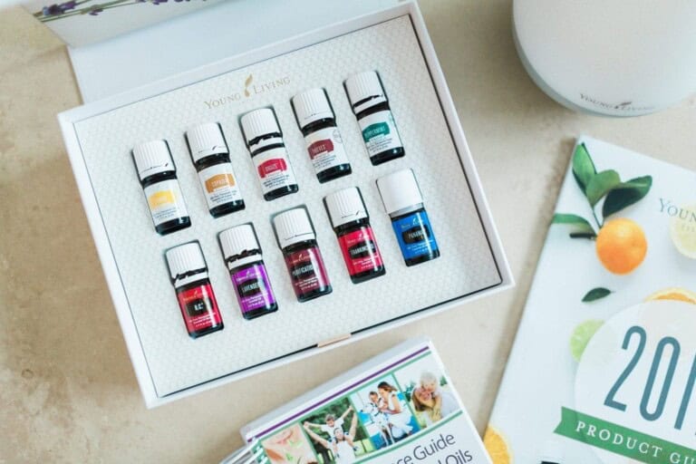 A box of Young Living essential oils contains ten small bottles arranged in two rows. Nearby are two booklets titled "2016 Product Guide" and "Essential Oils." A diffuser is partially visible in the corner, ideal for those considering essential oils while pregnant.