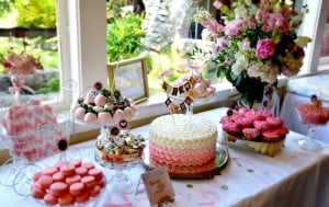 Decorated baby shower dessert table with cake, flowers, and treats in pink and gold