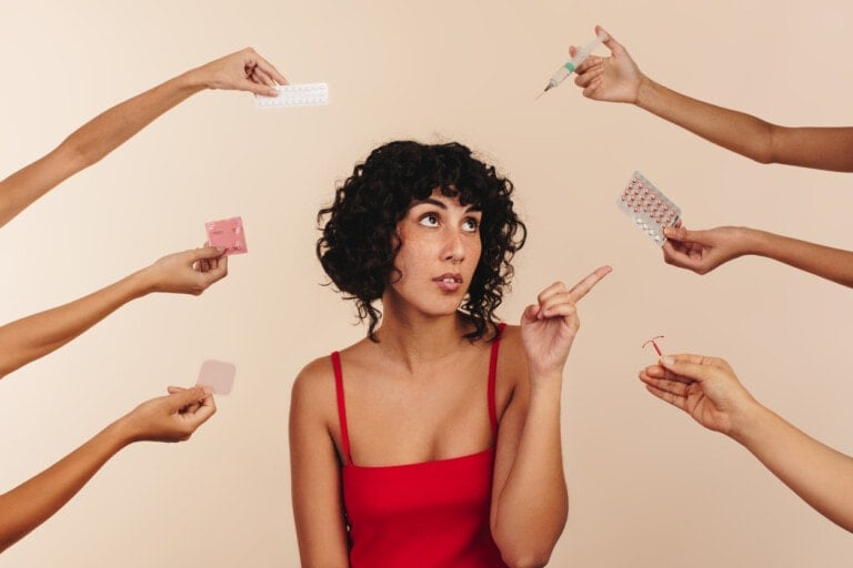 A person with curly black hair and a red sleeveless top is surrounded by multiple hands holding different forms of postpartum birth control, including pills, a shot, a patch, an IUD, and a condom. The person is looking up and to the side while pointing.