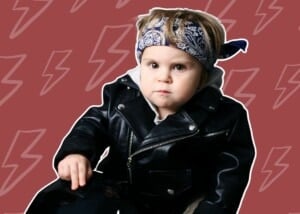 A child with a serious expression wearing a black leather jacket and a blue patterned bandana. The background is a muted red color with lightning bolt graphics, perfectly setting the stage for anyone considering badass boy names.