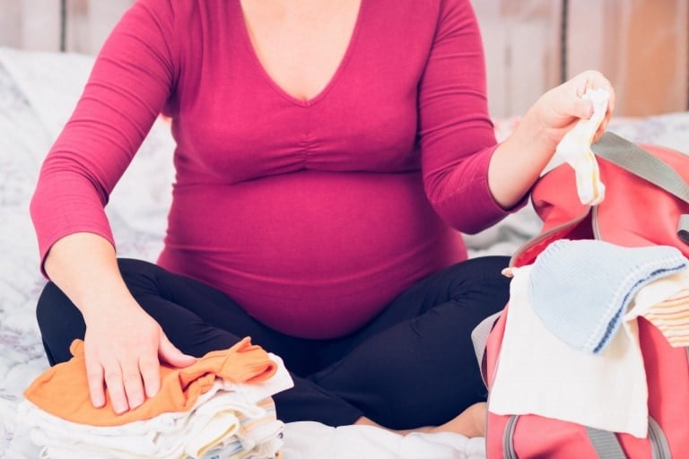 Pregnant woman packing hospital bag for labor and delivery