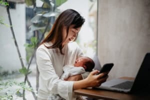 Image of an Asian Chinese woman working at home while taking care of her newborn baby at home